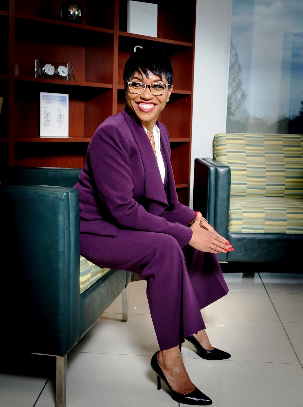 Woman in purple suit sitting on chair.